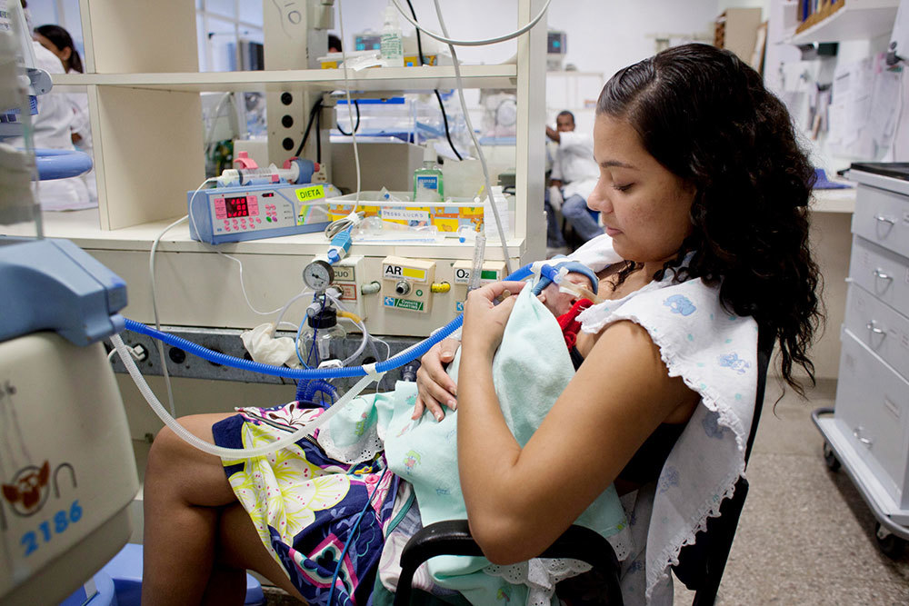 A picture of a woman feeding a baby milk in a medical setting