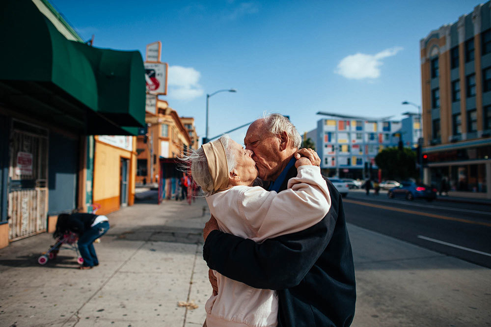 An older man and a woman kiss on the street