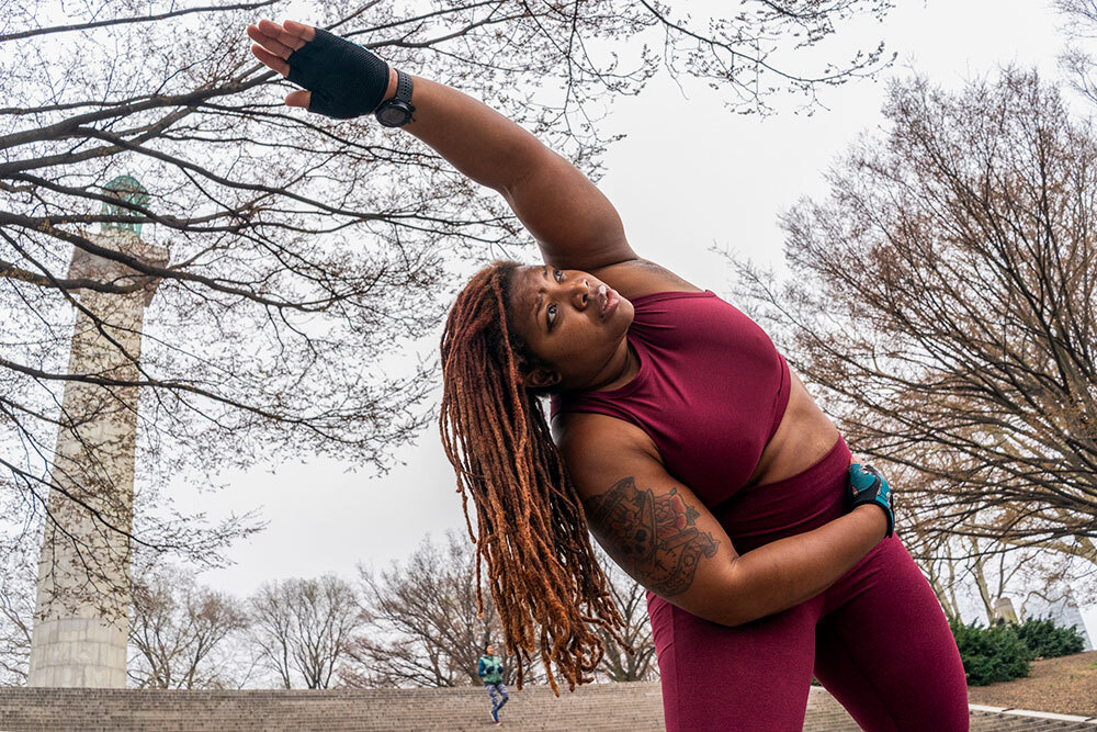 a woman in a red workout outfit stretches outside on a cloudy day