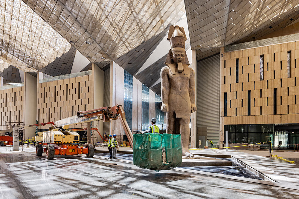 A large statue of a pharaoh stands in a modern building