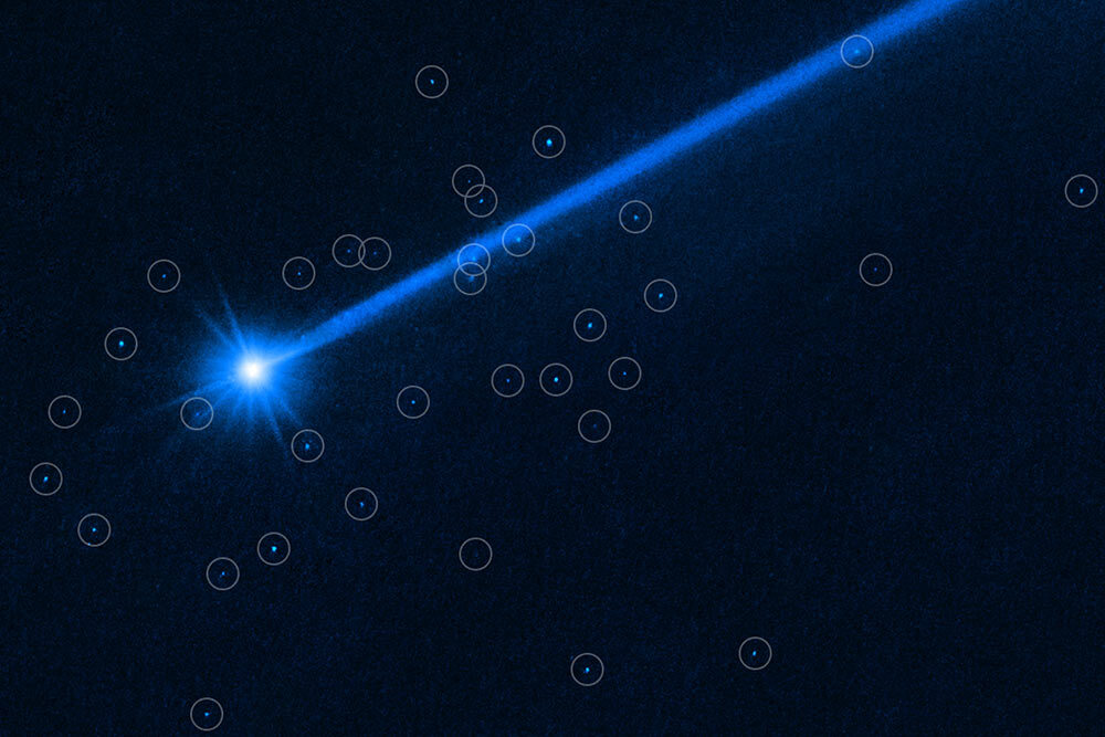 A Hubble Space Telescope image of the asteroid Dimorphos surrounded by boulders (tiny bright dots, circled) that were knocked off of the asteroid’s surface by NASA’s DART mission.