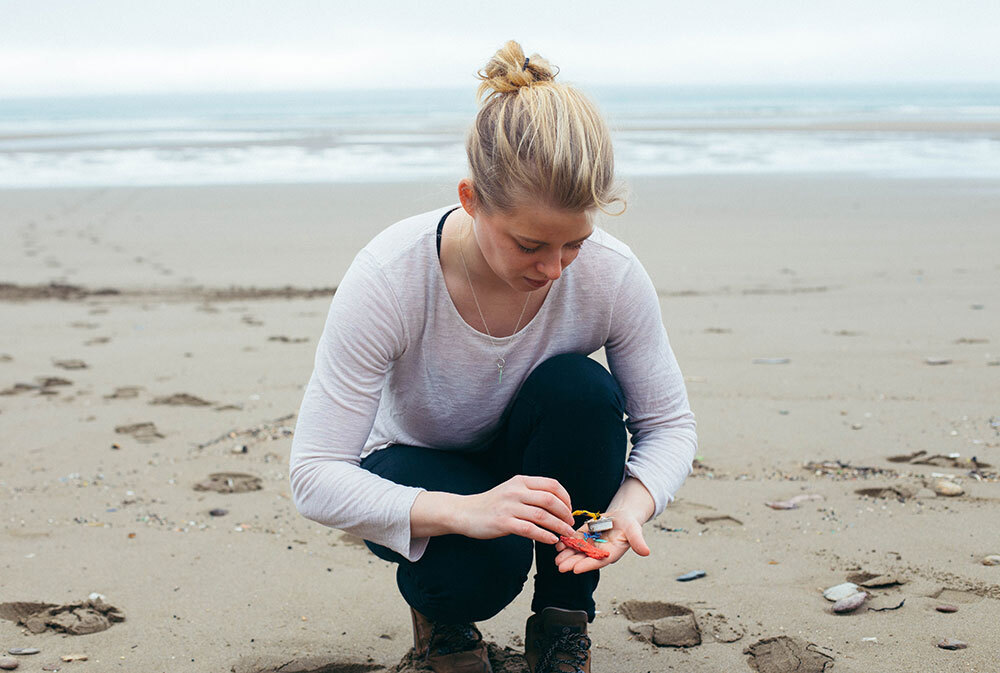 A woman collects plastic from a beach