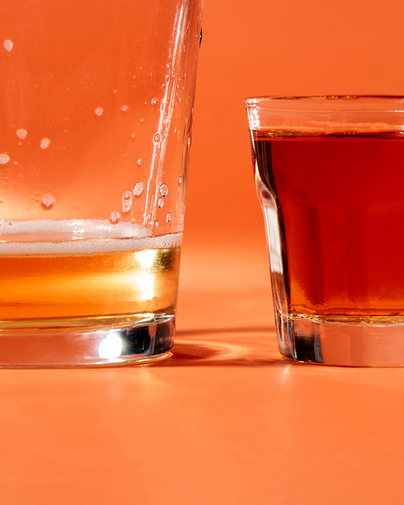 A photo of beer and liquor against an orange studio background