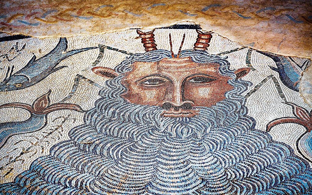 A mosaic on the wall shows a man with a long flowing white beard and horns