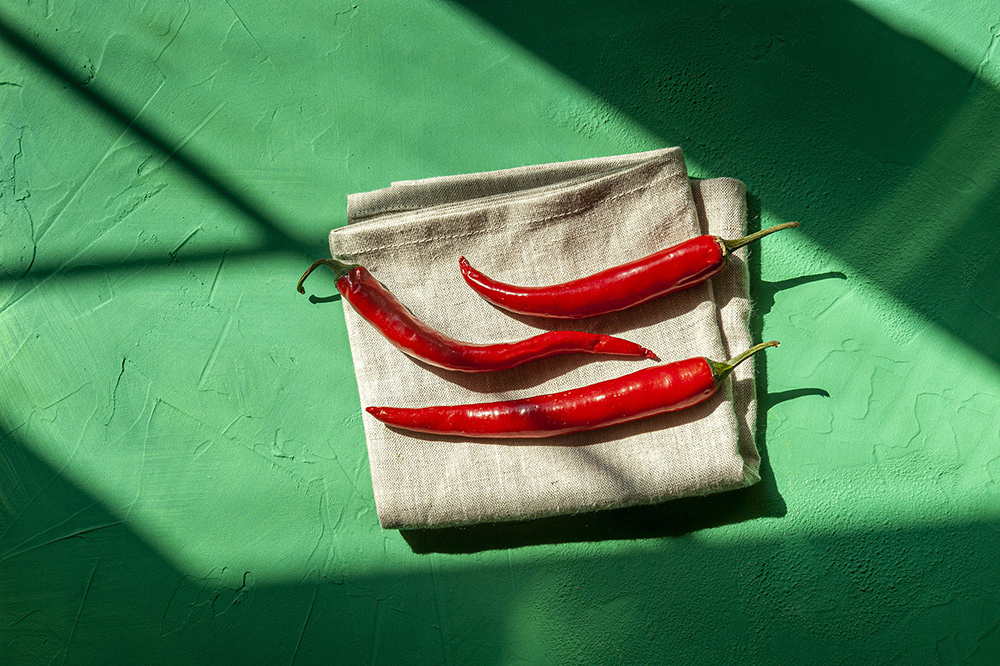 Three red chili peppers on a green background