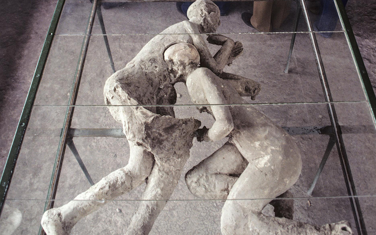 A group studies body casts in the House of Cryptoporticus while touring the ruins of Pompeii. In addition to this city near modern-day Naples, the port town of Herculaneum and many other sites near Mount Vesuvius were buried by its pyroclastic flows and surges in A.D. 79.