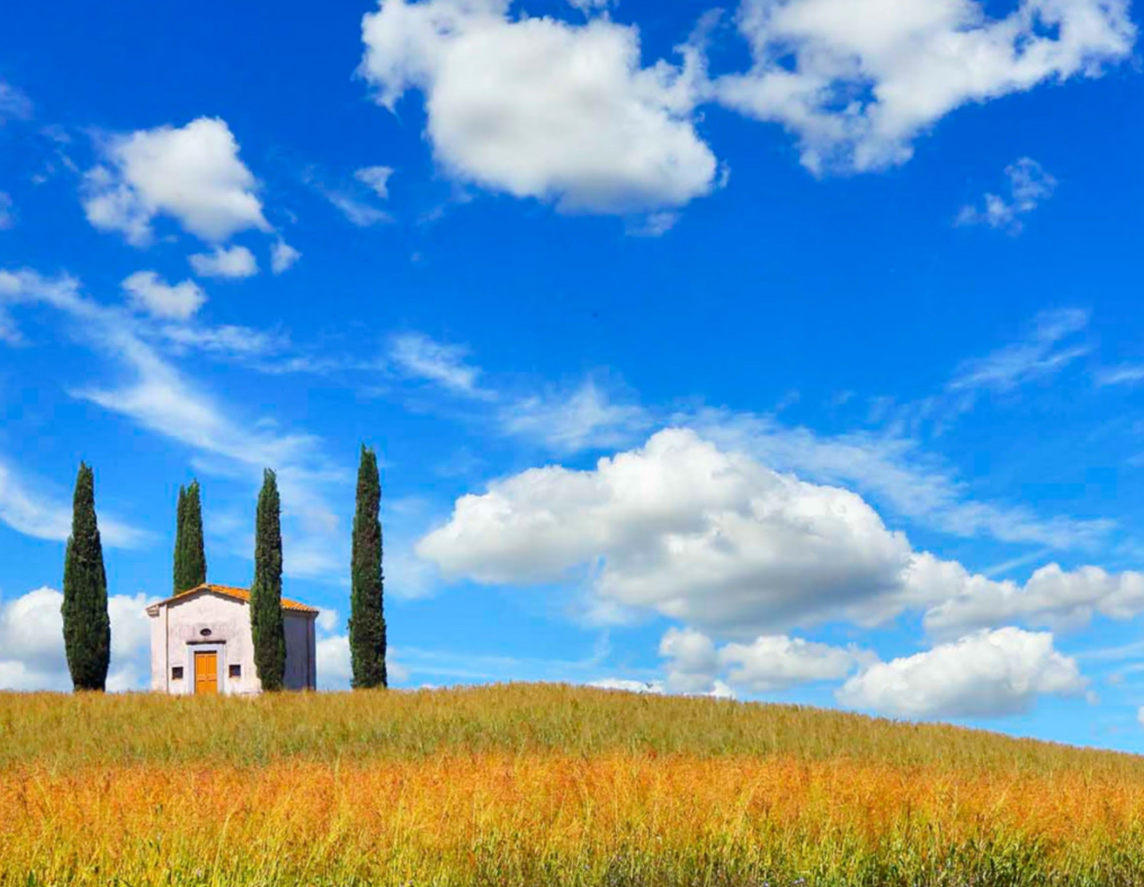 a small country church and cypress trees in Valdera valley, Tuscany, Italy