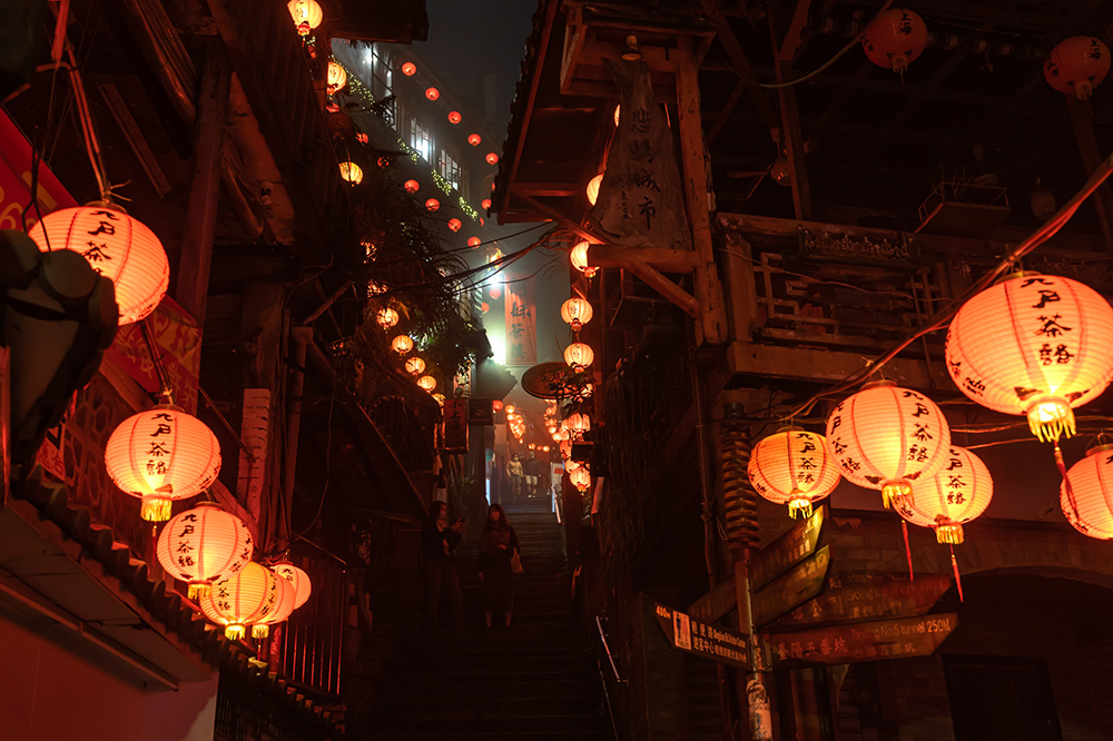 Visitors explore Jiufen's tight winding alleyways lit by traditional hanging lanterns