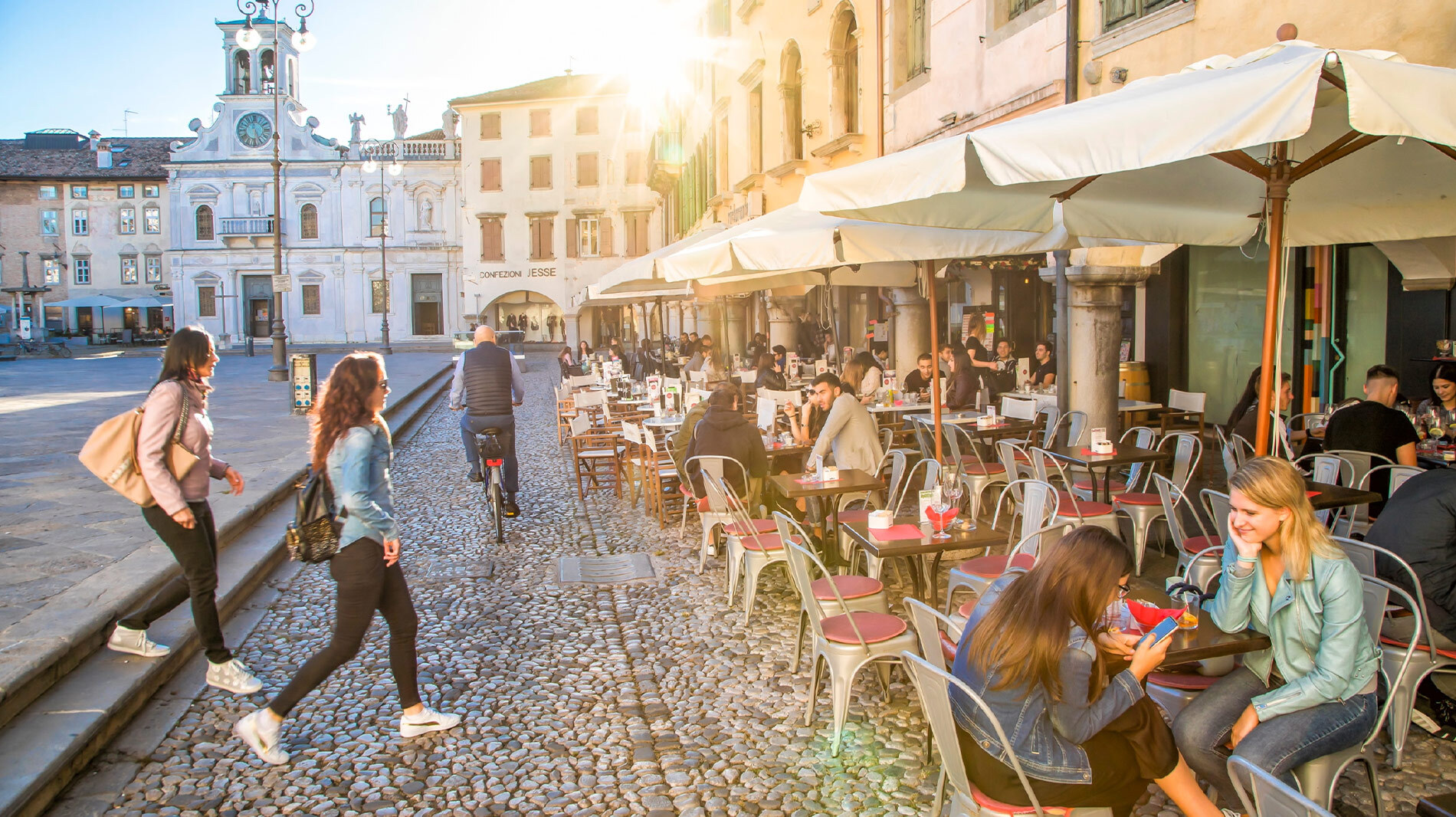 Locals socialize at Versus, a wine bar and cafe overlooking Piazza Giacomo Matteotti and Chiesa di San Giacomo (left) in Udine, Italy.