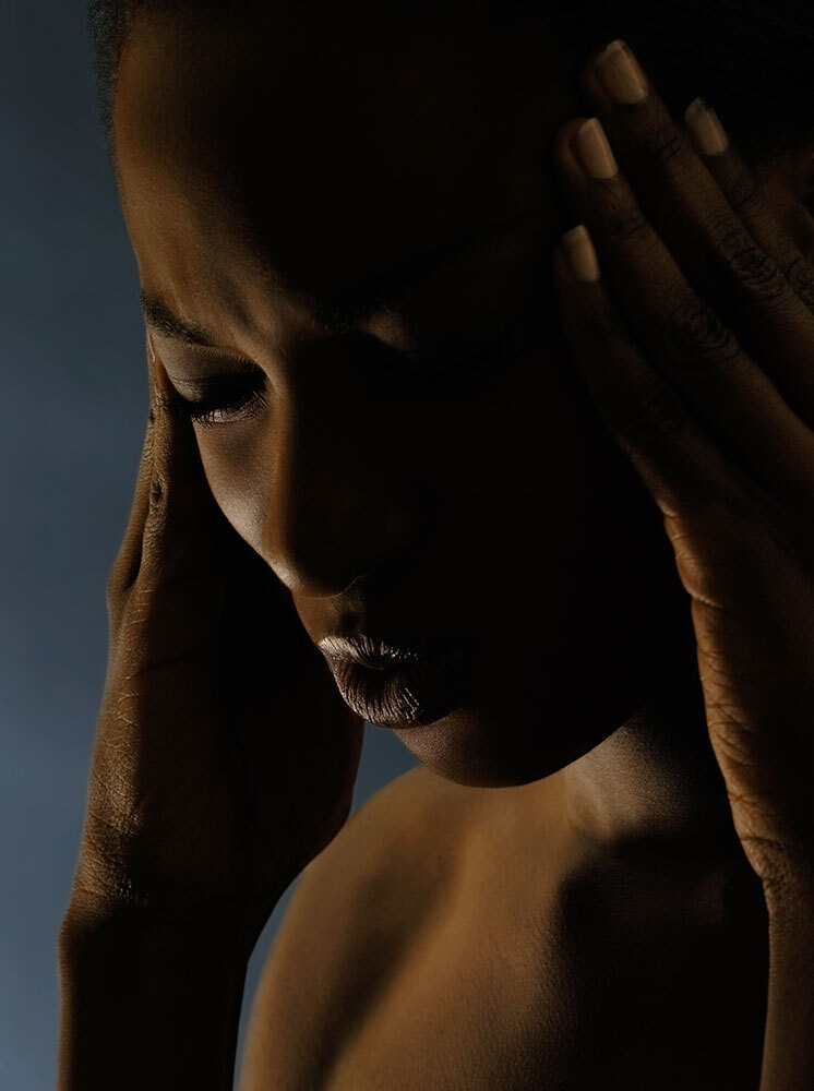 A woman holds her head at her temples