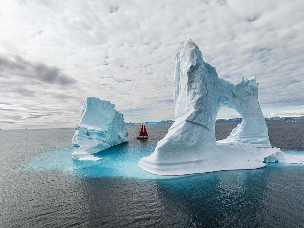 A boat sails near an iceberg