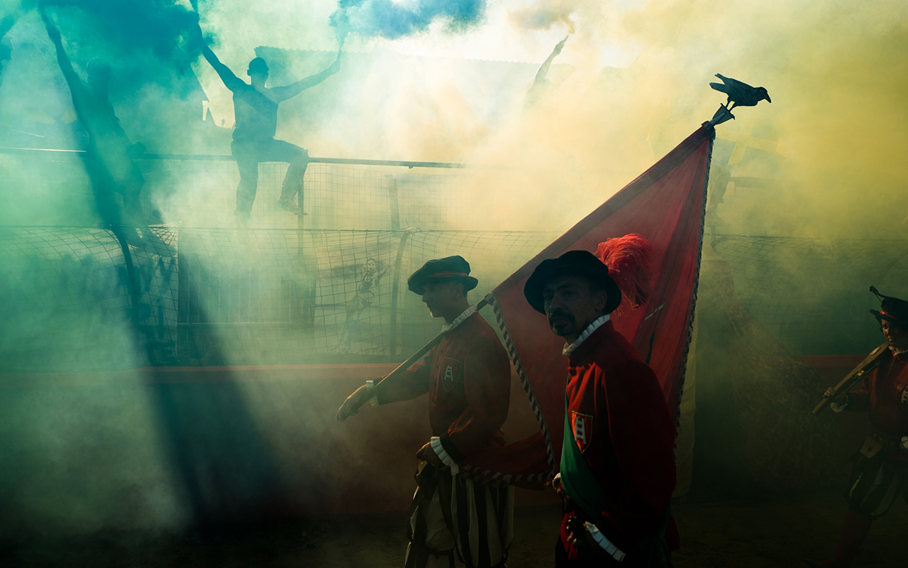 Supporters of the Azzurri team, which represents the city's Santa Croce quarter, celebrate with their team color, blue, as participants in the corteo, or traditional procession, pass wearing medieval garb.