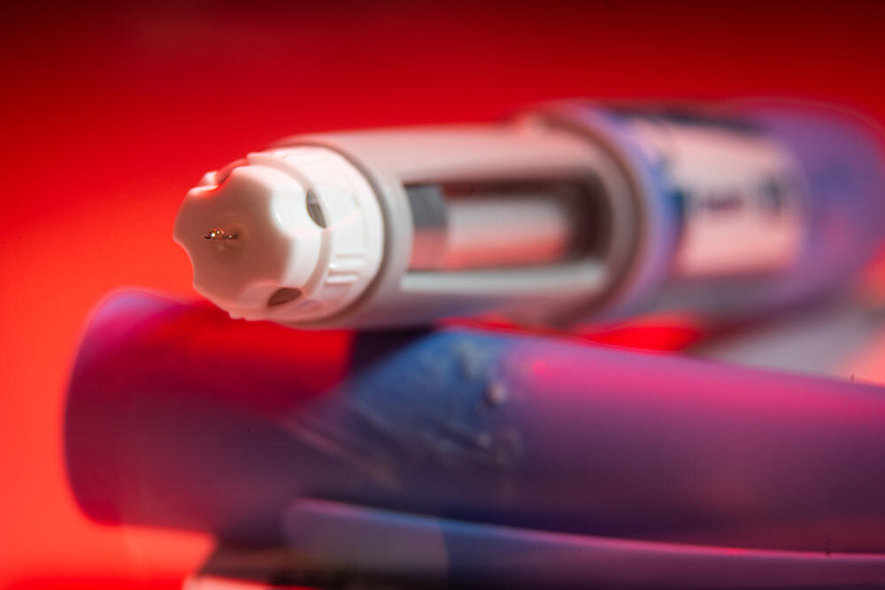 An Ozempic needle injection pen photographed against a red background