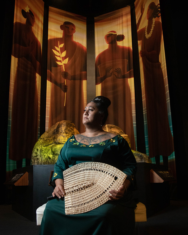 Hinaleimoana "Kumu Hina" Wong-Kalu, co-curator of The Healer Stones of Kapaemāhū exhibit, in front of a life-size rendering of Nā Pōhaku Ola Kapaemāhū a Kapuni at the Bernice Pauahi Bishop Museum in Honolulu, HI