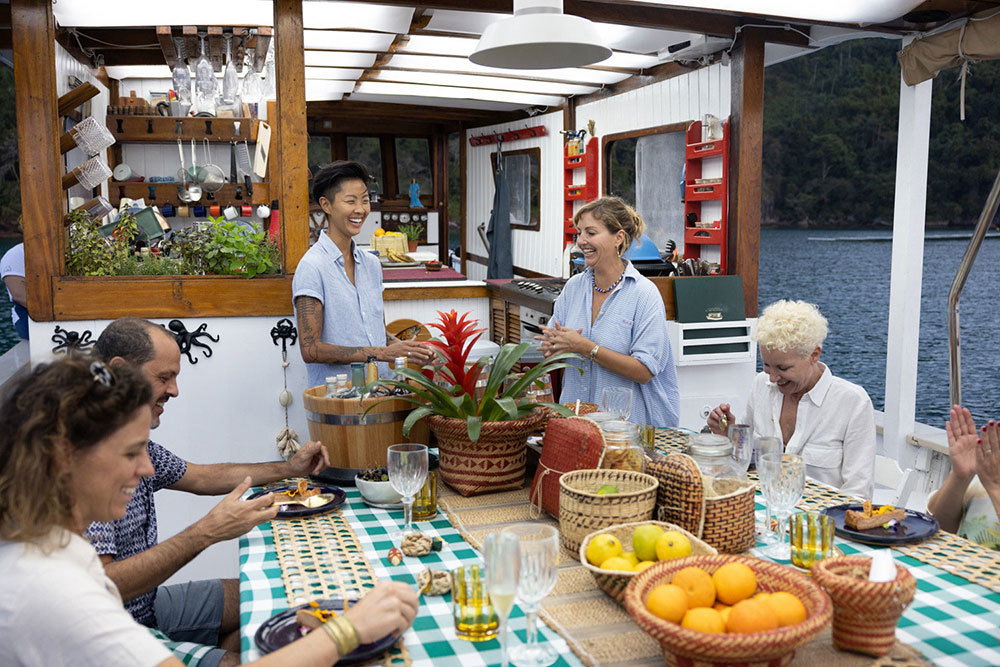 Kristen Kish and Gisela Schmitt share a meal with guests on a boat in Brazil