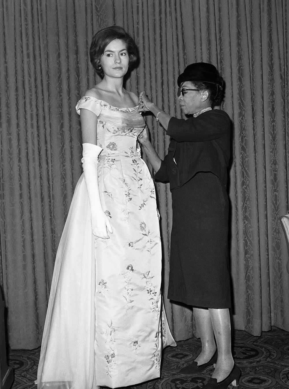 Ann Lowe was the secret weapon of 20th century American socialites, designing debutante gowns and wedding dresses for the nation's top families—including future First Lady Jackie Kennedy. In this image, she adjusts the bodice of a gown worn by Alice Baker.