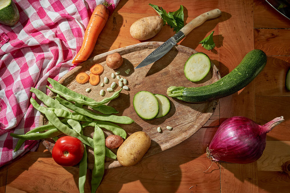 A spread of vegetables on a chopping board and a table