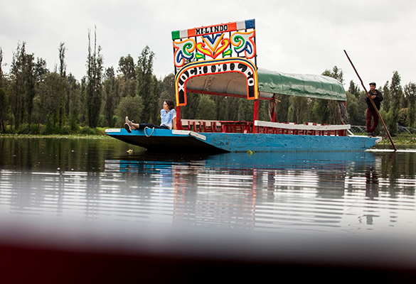 A tourist gazes out from the bow of a “trajinera,” a colorful barge that offers tours through Mexico City’s famed—yet endangered—Xochimilco canals.