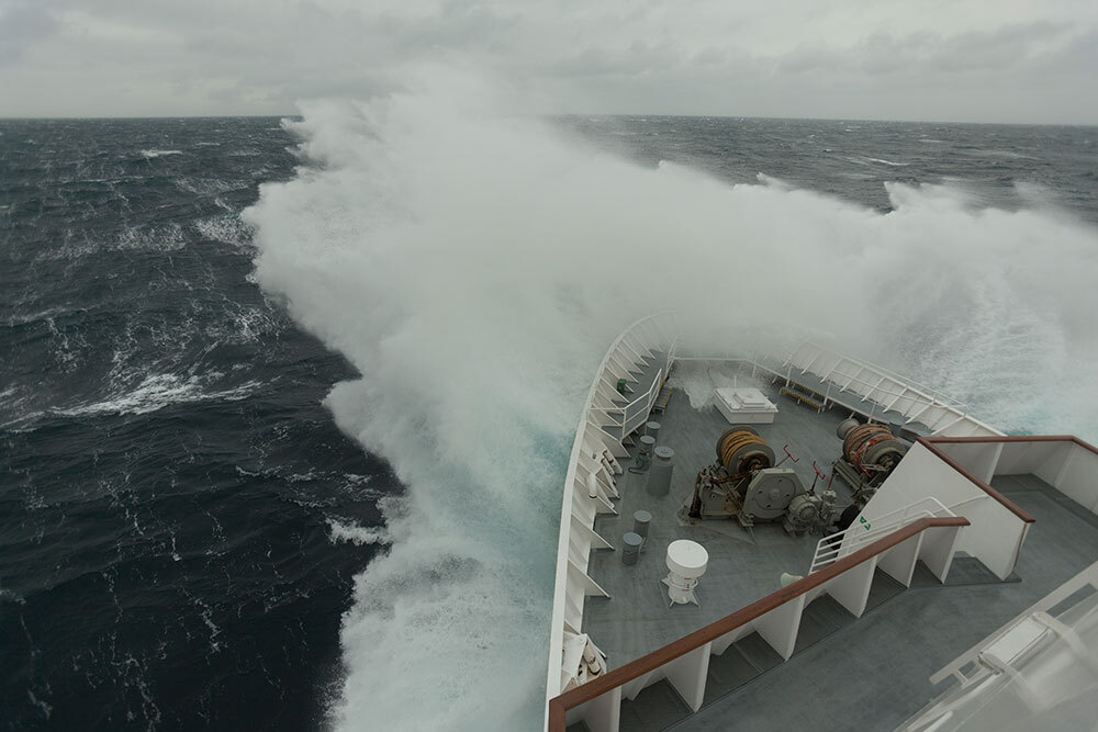 Waves crash against a cruise ship maneuvering through the Drake Passage.