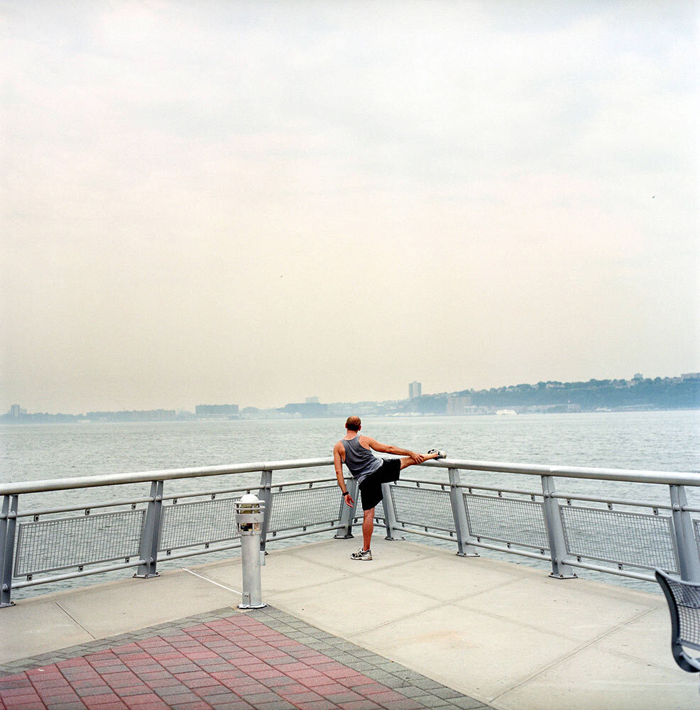 A man stretches in front of the Hudson River, NY.