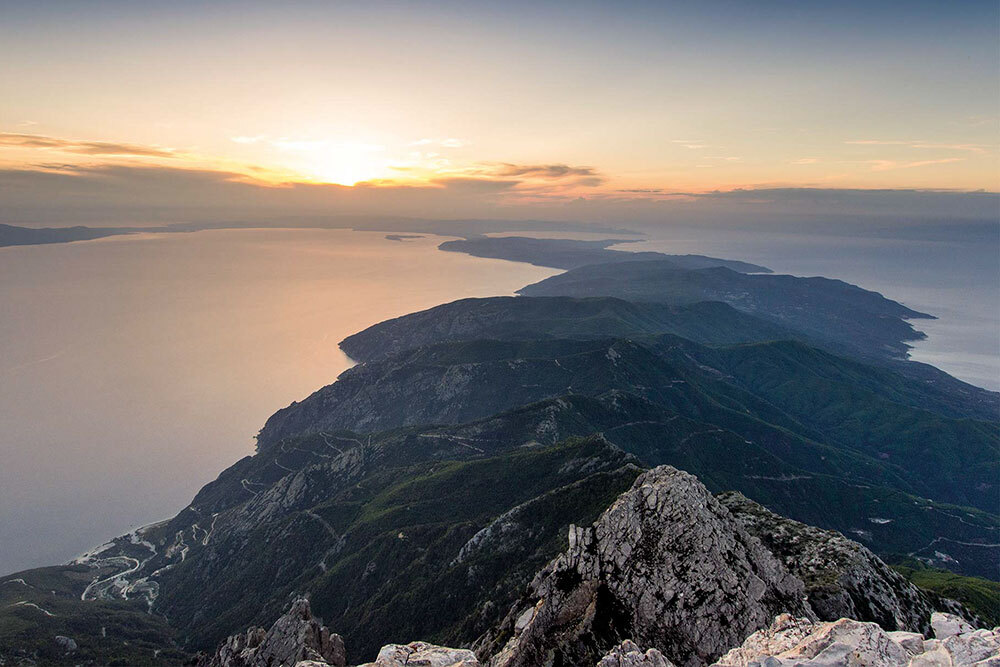 a view of mountains and water from Mount Athos in Greece at sunset