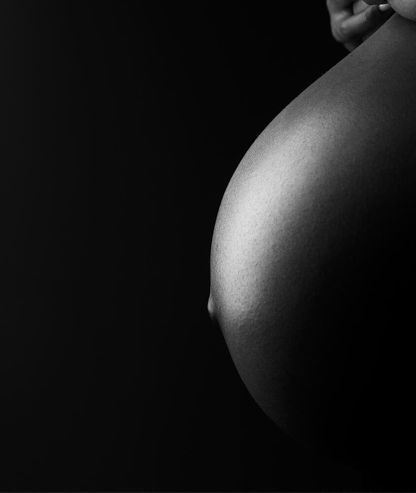 A profile view of a woman's belly while pregnant in black and white.