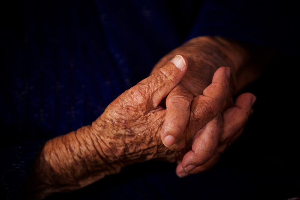 A pair of aged and wrinkled hands are seen close up.