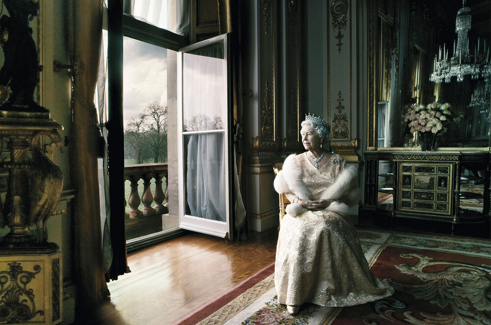 Queen Elizabeth as an older lady sits in a gown near a window