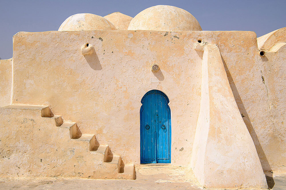 An earthen house with a bright blue door
