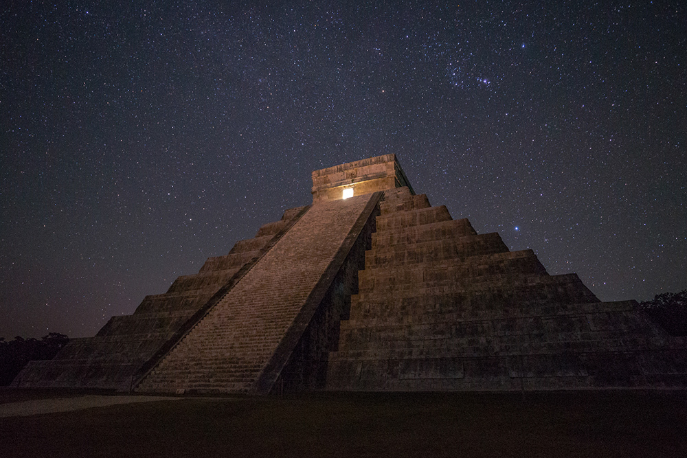 The Great Pyramid beneath a starry sky, the upper chamber illuminated with golden light