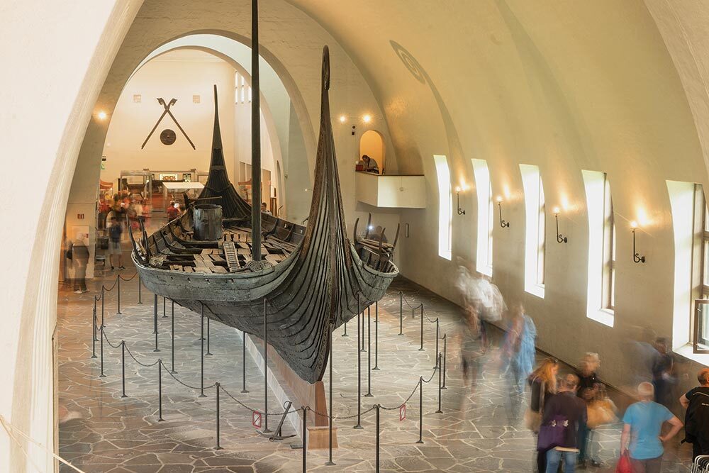 People in a museum walk past a Karve, a type of Viking longship that could be both sailed and rowed.