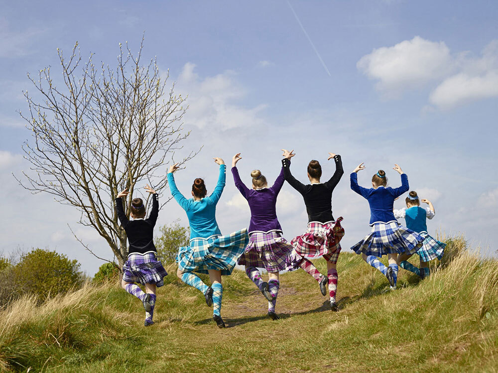 Girls in tartan dance on grass