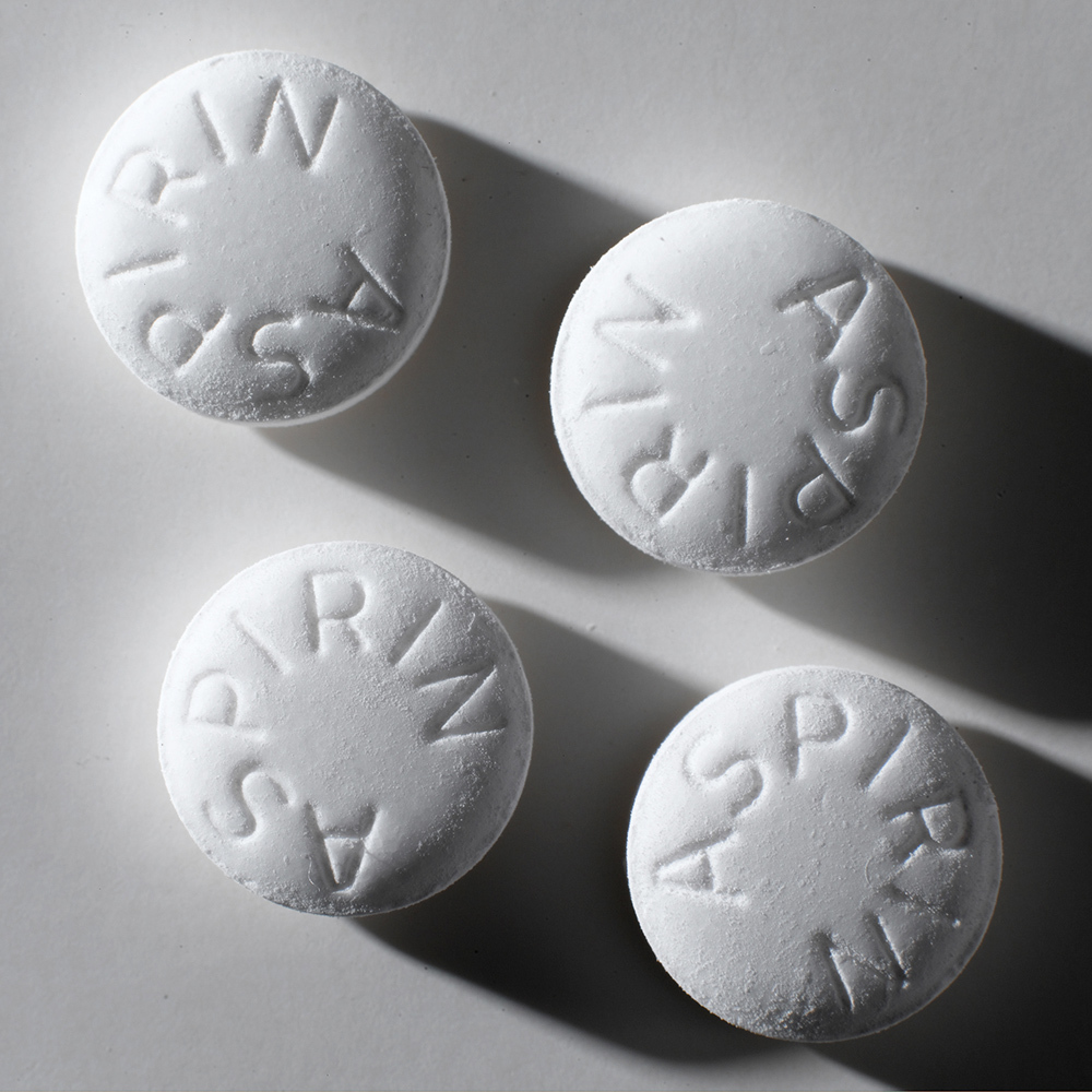 Four white aspirin tablets on a white background