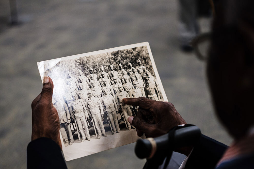 A picture of a person pointing to an old photograph of Marines.