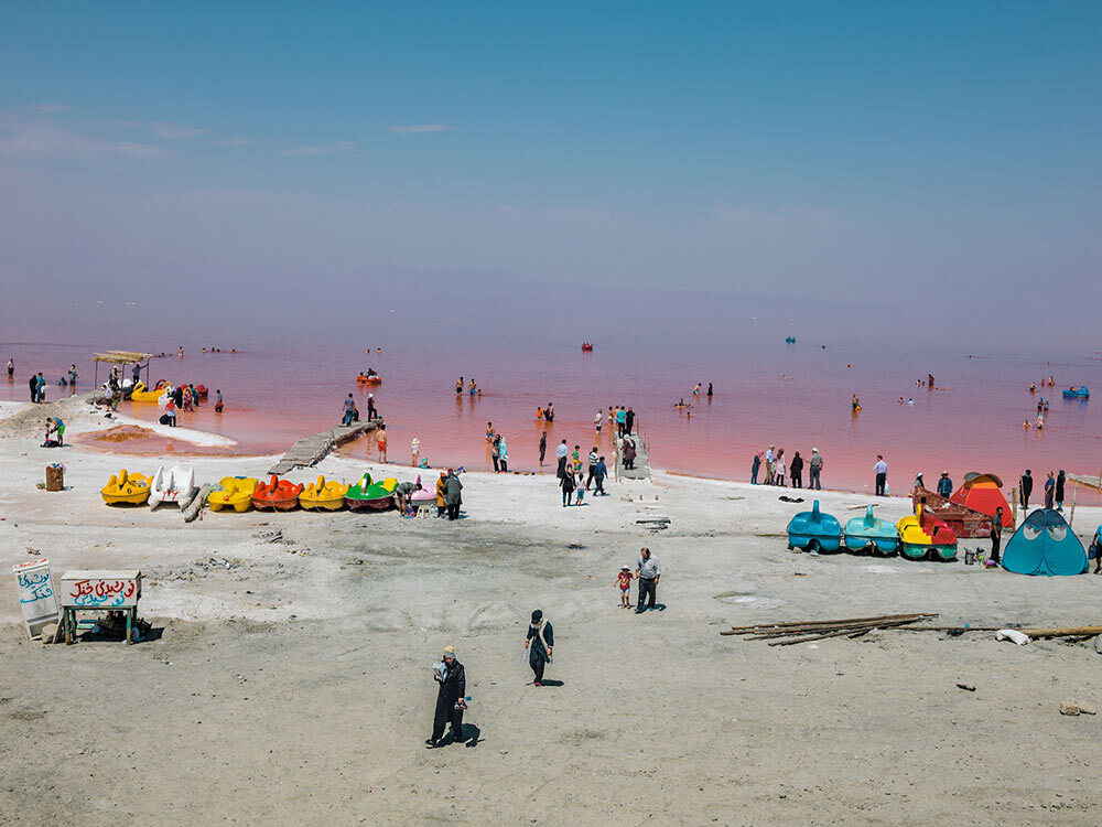 Summertime bathers wade into waters colored red by salt-loving bacteria and algae.