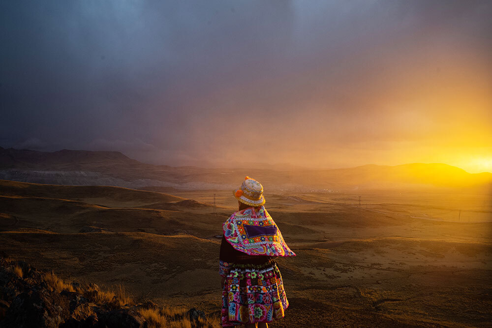 A woman overlooks a sunset blanketing hills