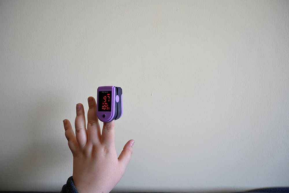 A medical student who suffers from Postural Orthostatic Tachycardia Syndrome (POTS) checks her pulse with an oximeter while she lies on the couch in her apartment. For patients with POTS, intermittent heart-rate monitoring is a daily routine.