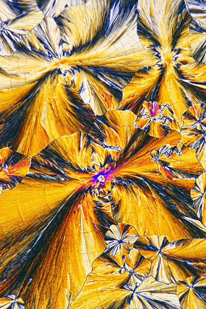 Light micrograph of ketamine, crystallized from aqueous solution, showing hues of gold with streaks of blues and purples.