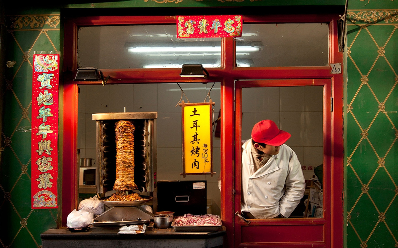 A vendor peers out the window of his stall on Wangfujing Snack Street in Beijing, China.