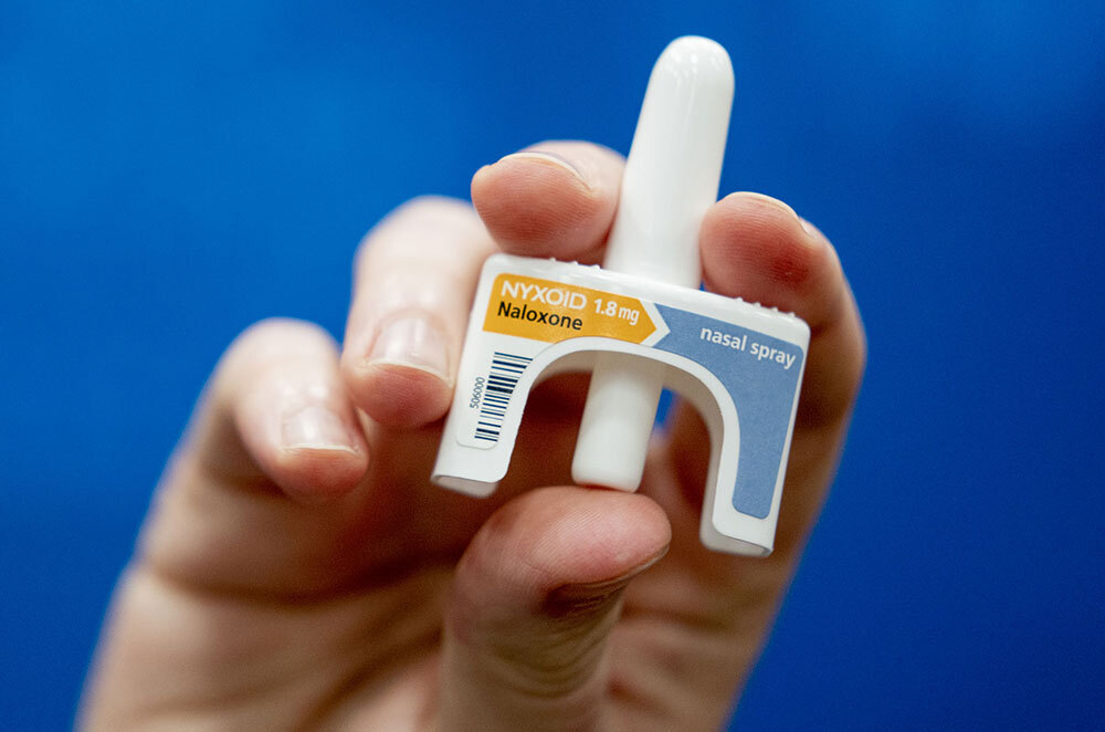 A picture of a hand holding a Narcan container