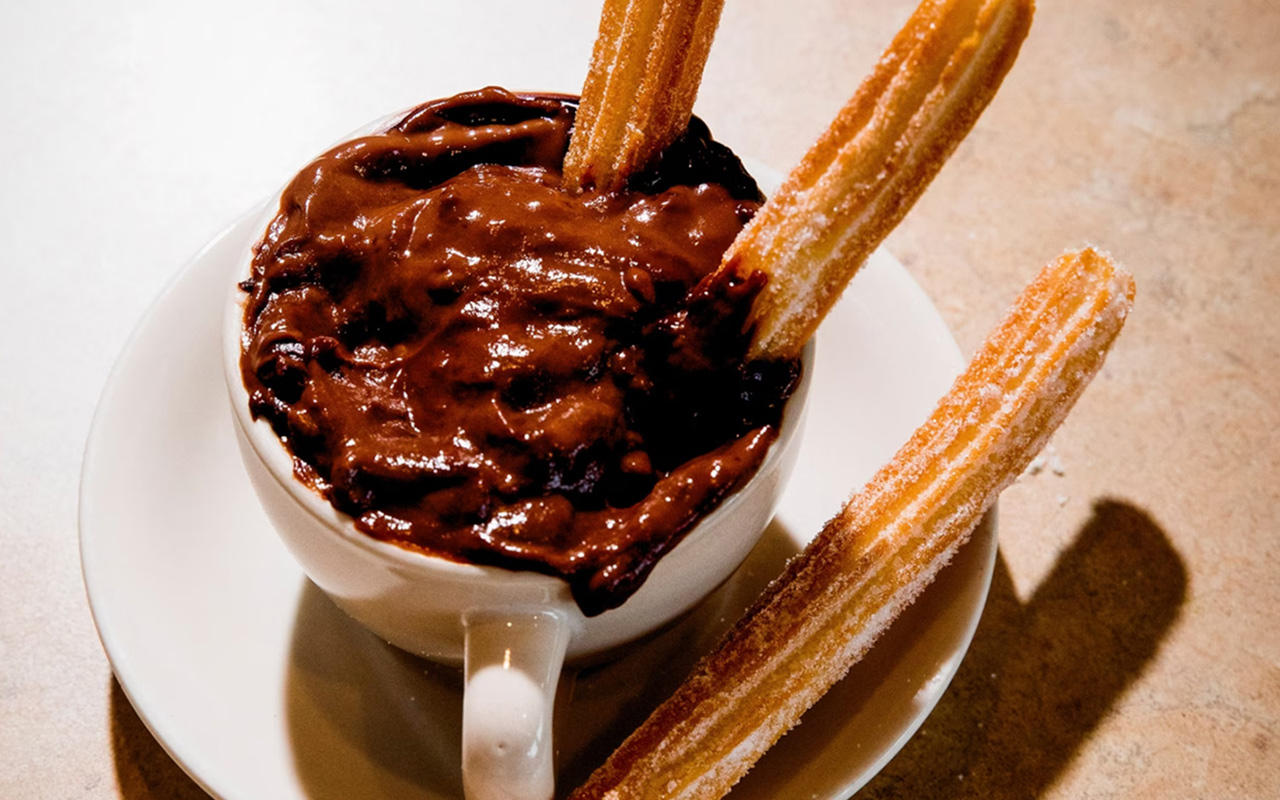 Diners enjoy churros coated in sugar and dipped in rich hot chocolate at La Palma, a Cuban restaurant in Miami.