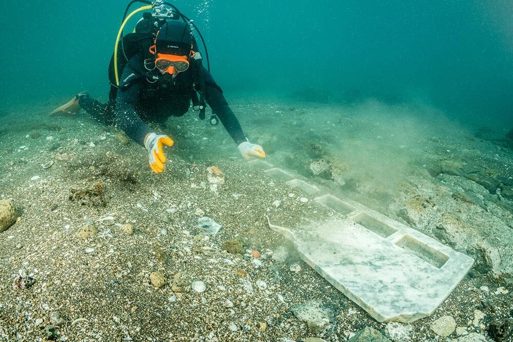 An archaeologist waves away sediment from the remains of a white marble altar in the waters off Puteoli, Italy.