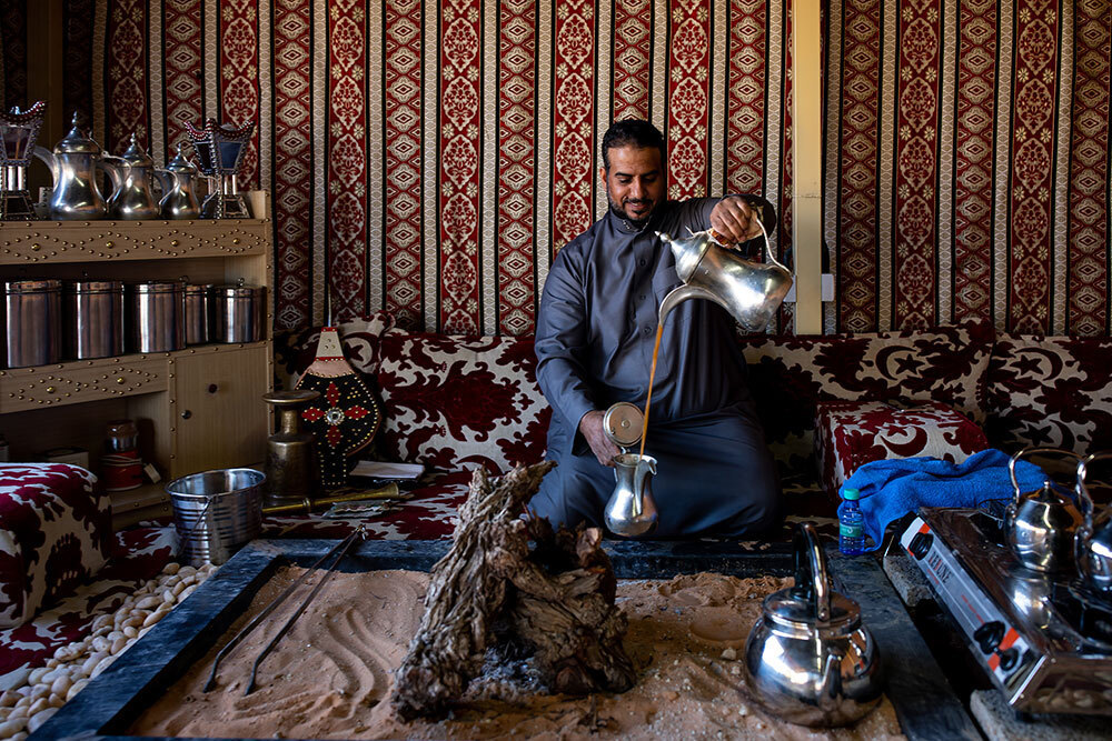 A person pours coffee between two pots