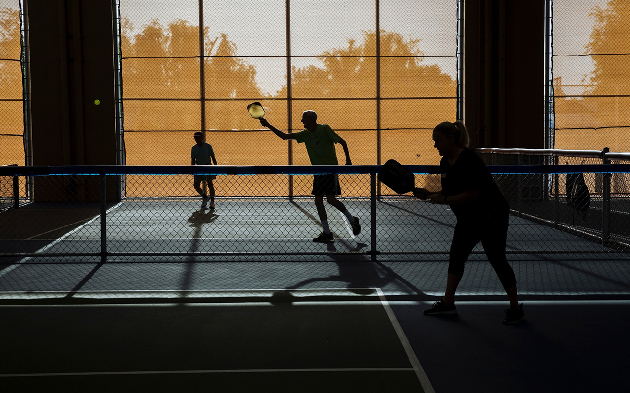 Members of the Sun City Pickleball Club are silhouetted as the morning sun filters through the shades at the Marinette Recreation Center in Sun City, Arizona.