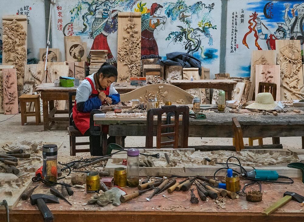 Carpenter Li Mingli chisels traditional bas-relief panels in Yangcen village. This workshop employs hearing-impaired craftspeople. On his trek in Yunnan, Salopek encountered workers with manual skills that hark back to past eras: beekeepers, chili grinders, handweavers, stonemasons.