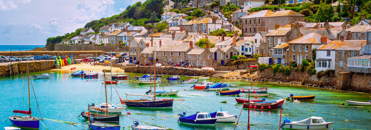 Fishing boats teem in a turquoise harbor on England's Cornwall coast.