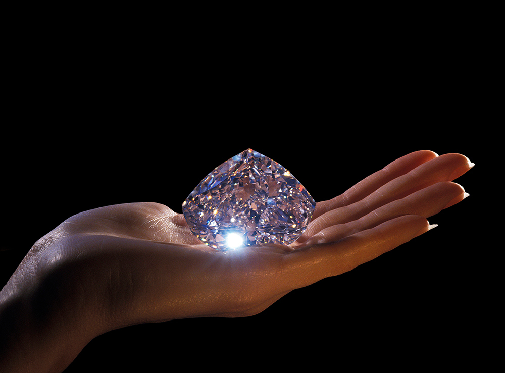 A gigantic diamond rests on the palm of a hand