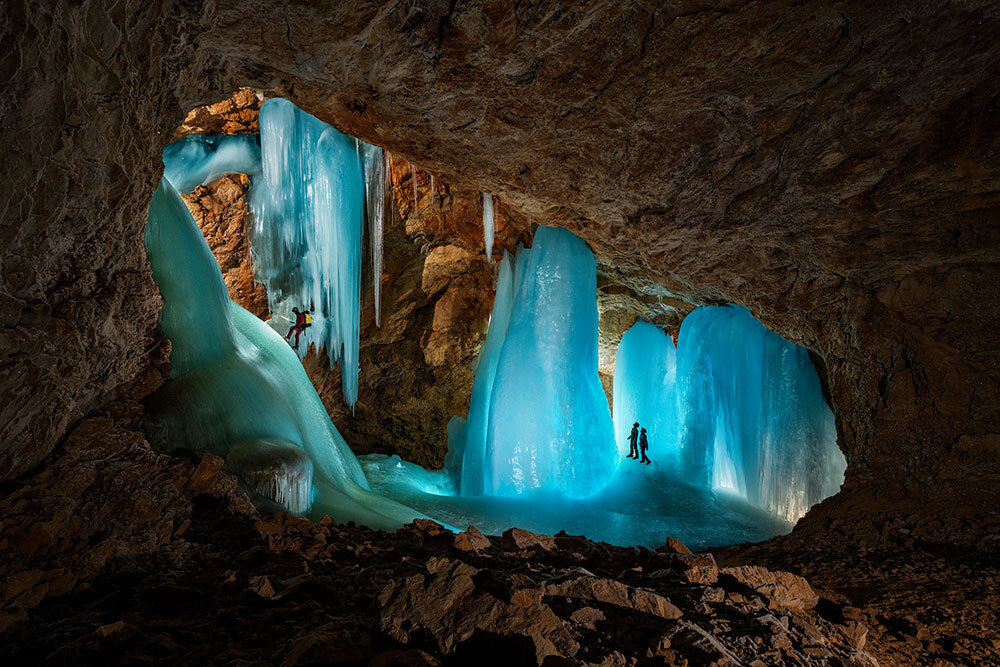 A photo of people walking on glowing ice in a cave