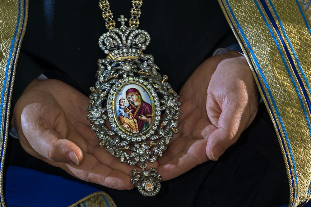 A picture of a jeweled necklace with a picture of Jesus and Mary on it