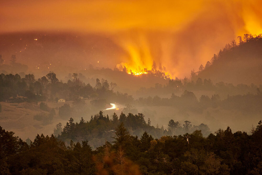 Orange light from a wildfire illuminates the night sky